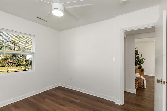 empty room featuring dark wood-style flooring, visible vents, ceiling fan, and baseboards