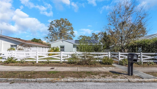 view of front facade featuring a fenced front yard, roof mounted solar panels, and a gate