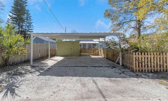 view of car parking with driveway, fence private yard, and a carport