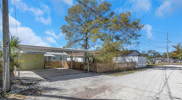 exterior space featuring dirt driveway, a carport, and a fenced front yard