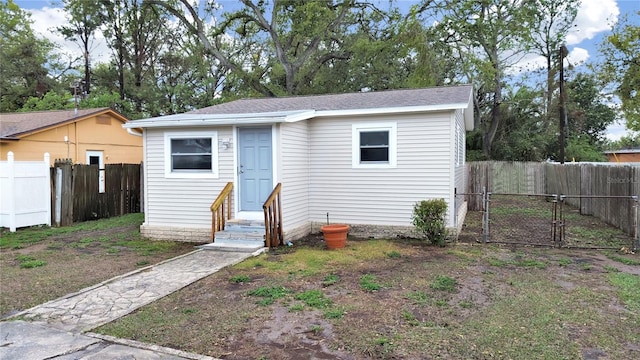 bungalow-style house featuring entry steps, an outbuilding, fence private yard, and a gate