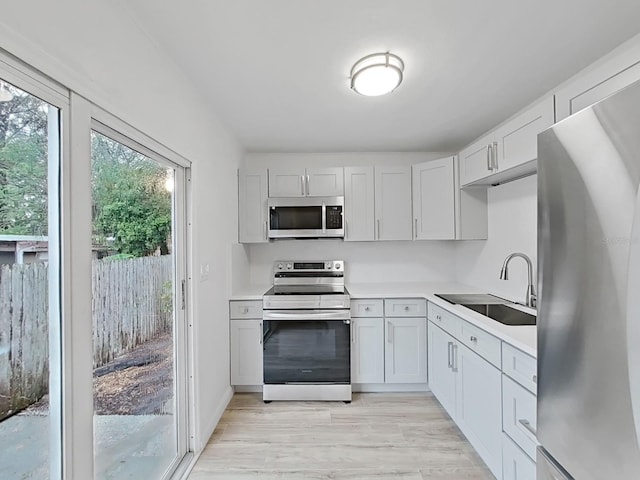 kitchen featuring light wood-style flooring, appliances with stainless steel finishes, light countertops, and a sink