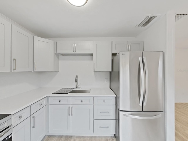 kitchen with a sink, visible vents, light countertops, light wood-type flooring, and freestanding refrigerator