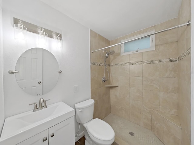 full bathroom with vanity, a tile shower, and toilet