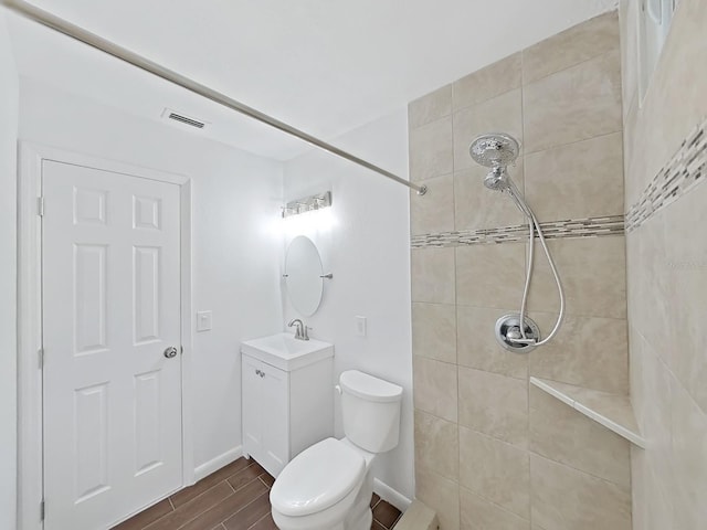 bathroom featuring wood finish floors, visible vents, a tile shower, and vanity