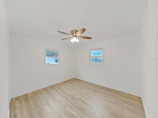 empty room featuring light wood finished floors, a wealth of natural light, and baseboards