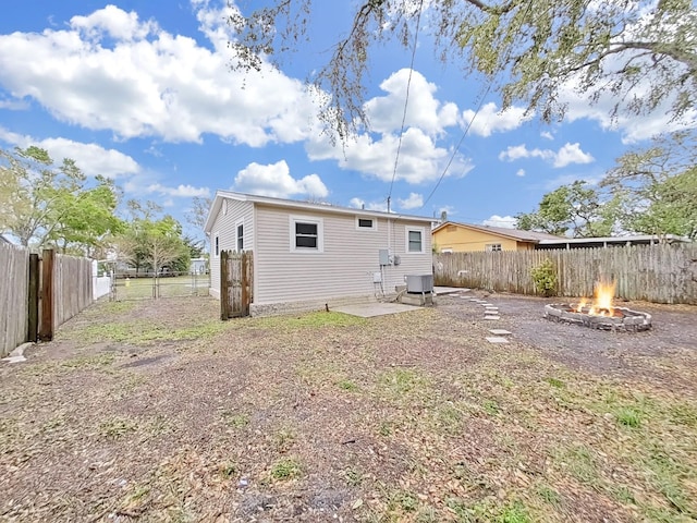 back of property with central AC unit, an outdoor fire pit, a patio area, and a fenced backyard