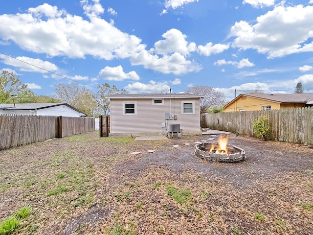 rear view of house with an outdoor fire pit, cooling unit, and a fenced backyard