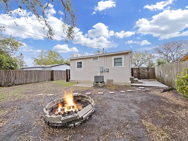 rear view of house with a fire pit and a fenced backyard