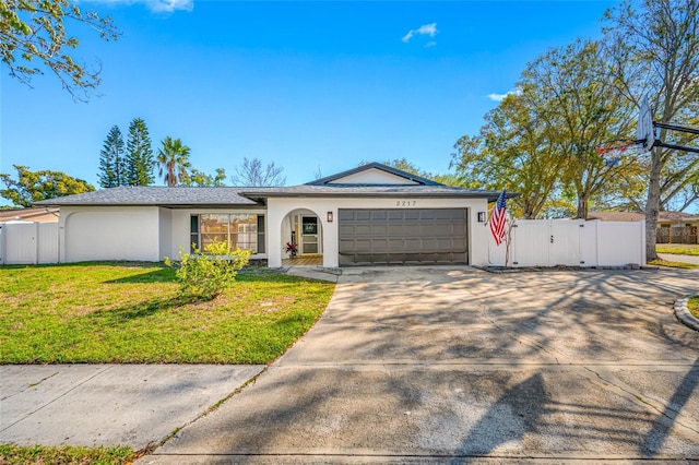 ranch-style house with an attached garage, driveway, a gate, stucco siding, and a front lawn