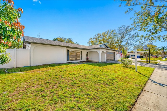 ranch-style home with an attached garage, fence, concrete driveway, stucco siding, and a front yard