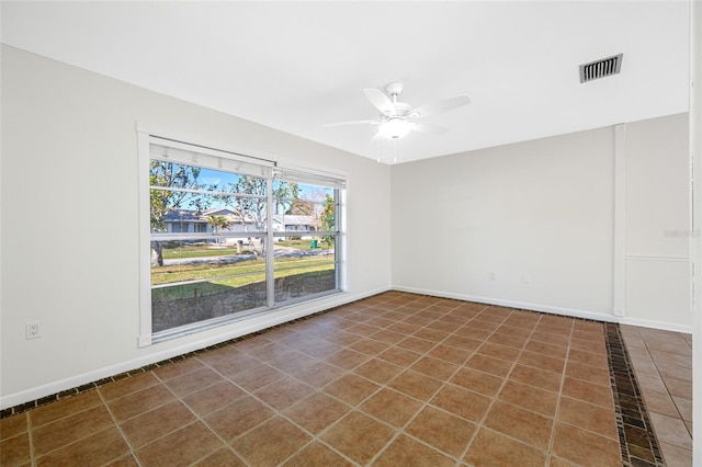 tiled spare room featuring baseboards, visible vents, and a ceiling fan