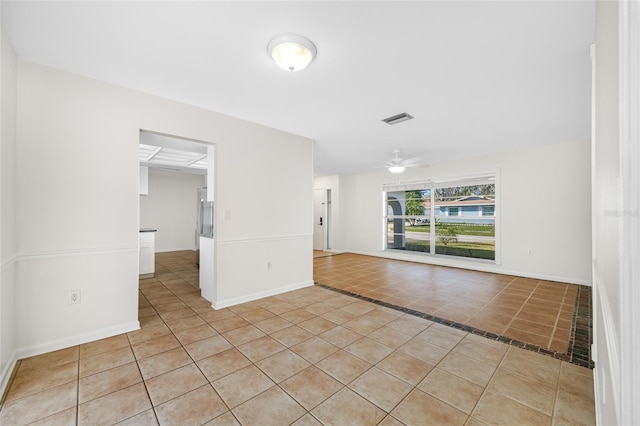 empty room with light tile patterned floors, ceiling fan, visible vents, and baseboards