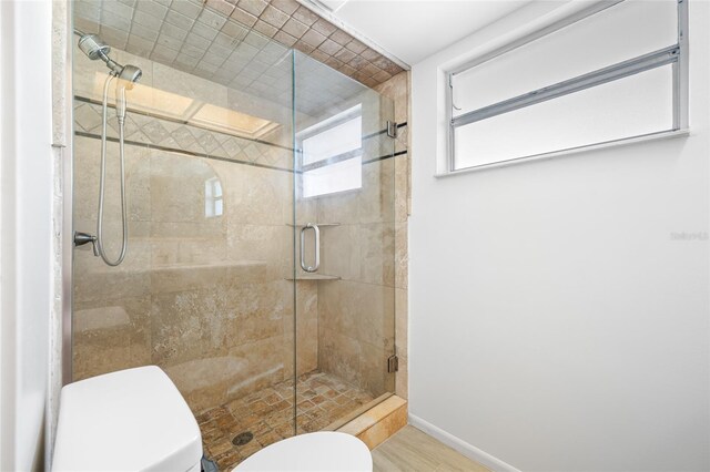 bathroom with baseboards, a shower stall, and toilet