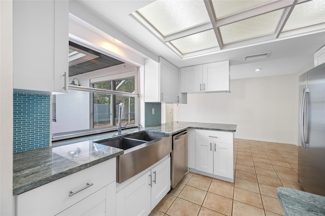 kitchen featuring stainless steel appliances, tasteful backsplash, a sink, and white cabinets