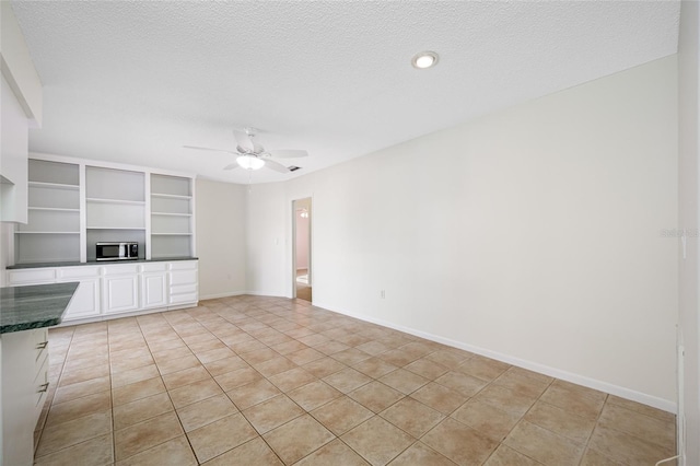 interior space with a textured ceiling, white cabinetry, a ceiling fan, open shelves, and stainless steel microwave