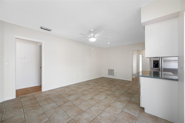 unfurnished living room featuring visible vents, ceiling fan, a textured ceiling, and light tile patterned floors