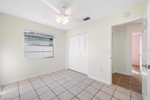 unfurnished bedroom with baseboards, visible vents, a ceiling fan, a closet, and light tile patterned flooring