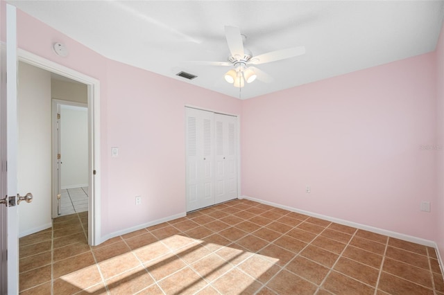 unfurnished bedroom with tile patterned flooring, visible vents, baseboards, a ceiling fan, and a closet