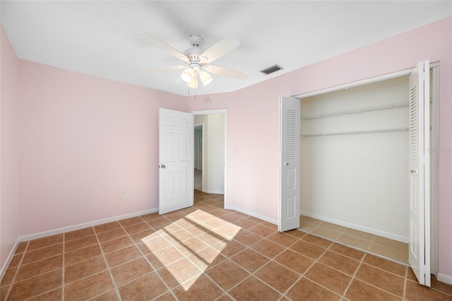 unfurnished bedroom with ceiling fan, tile patterned flooring, visible vents, baseboards, and a closet