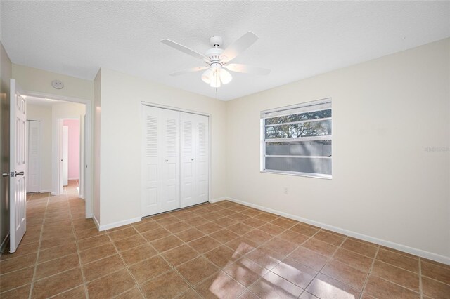 unfurnished bedroom featuring tile patterned flooring, a textured ceiling, baseboards, and a closet