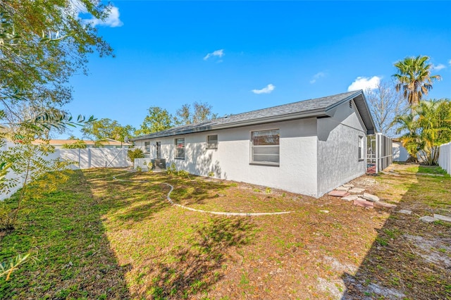 rear view of house featuring a fenced backyard, a lawn, and stucco siding