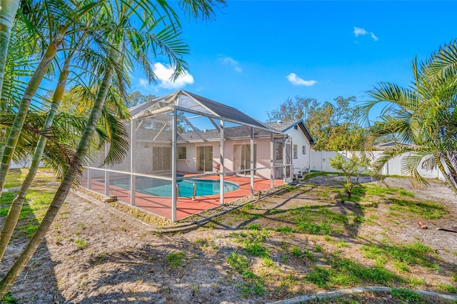 back of property with a lanai, a patio area, a fenced backyard, and an outdoor pool