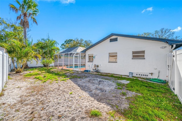 rear view of house featuring a fenced in pool, a lanai, a fenced backyard, and stucco siding