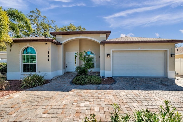 mediterranean / spanish-style house featuring decorative driveway, an attached garage, and stucco siding