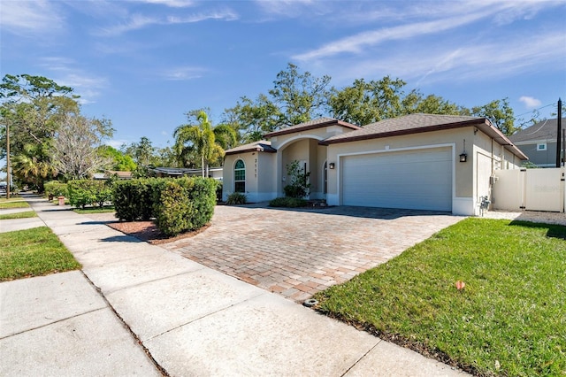 view of front of home featuring an attached garage, fence, decorative driveway, and stucco siding