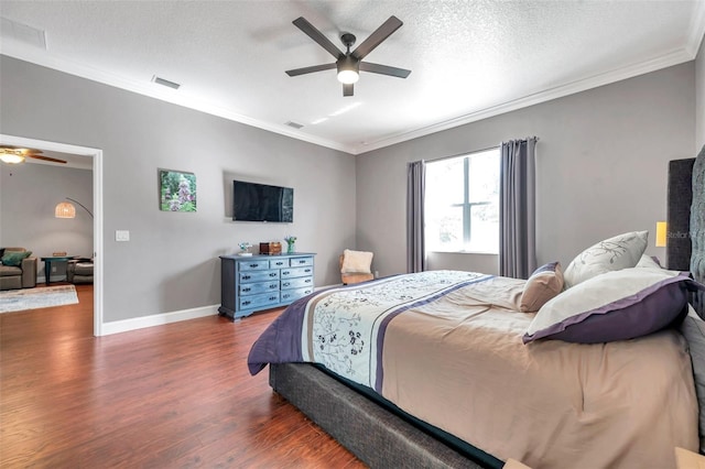 bedroom featuring a textured ceiling, wood finished floors, visible vents, baseboards, and ornamental molding