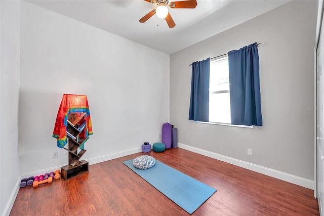 workout area featuring ceiling fan, baseboards, and wood finished floors