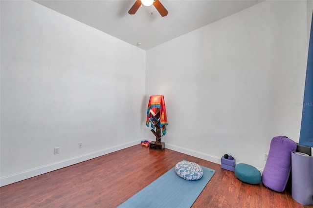 workout area with wood finished floors, a ceiling fan, and baseboards