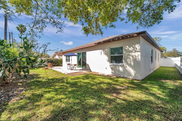 rear view of house featuring a yard, a patio area, a fenced backyard, and stucco siding