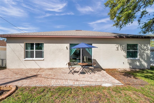 back of house with a patio area, roof with shingles, and stucco siding