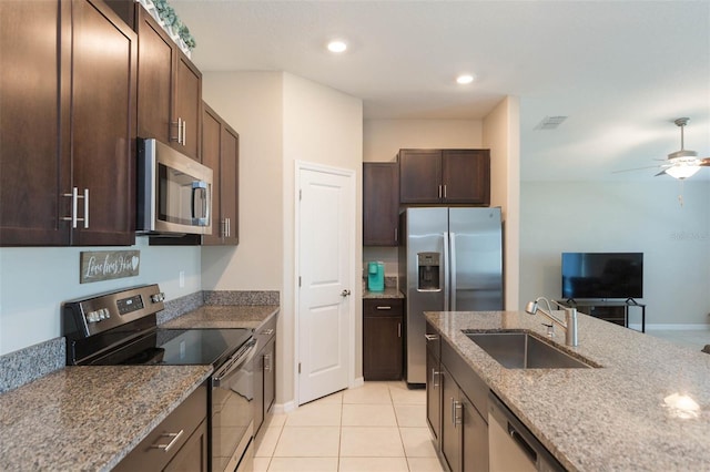 kitchen with dark brown cabinetry, stone countertops, visible vents, stainless steel appliances, and a sink