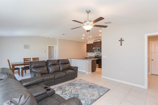 living room with light tile patterned floors, lofted ceiling, visible vents, ceiling fan, and baseboards