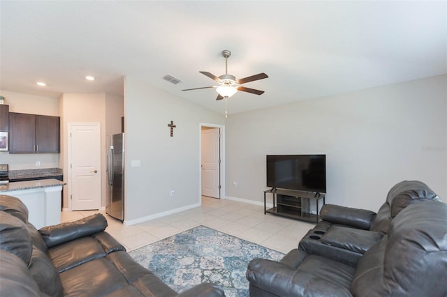 living area featuring light tile patterned floors, a ceiling fan, visible vents, vaulted ceiling, and baseboards