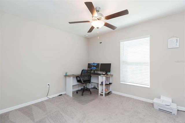 carpeted office space featuring baseboards and a ceiling fan