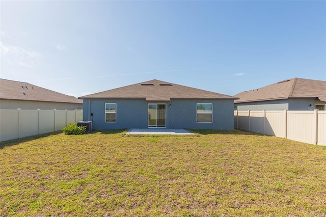 rear view of house with a fenced backyard, a yard, and stucco siding