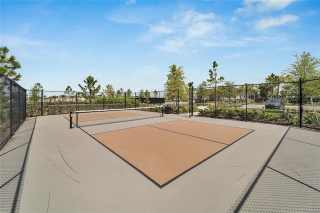 view of community featuring a tennis court and fence