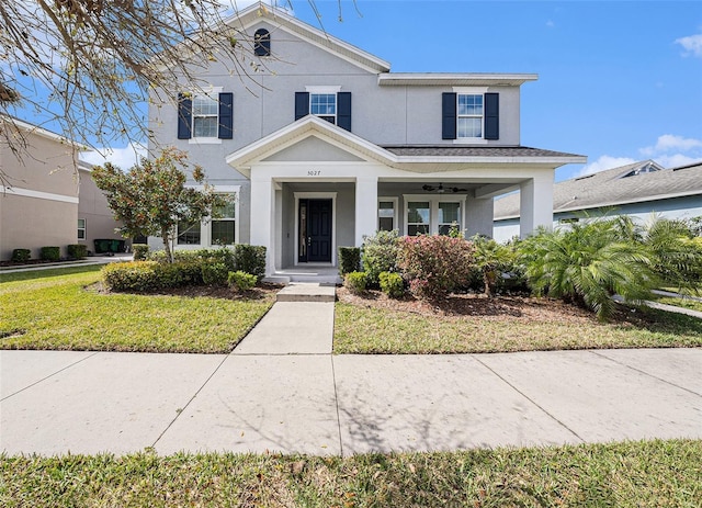 view of front of property with covered porch, a front lawn, and stucco siding