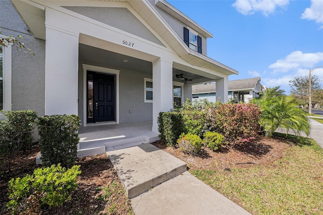 entrance to property with a porch and stucco siding