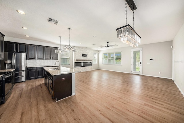 kitchen with visible vents, stainless steel fridge with ice dispenser, an island with sink, open floor plan, and a sink