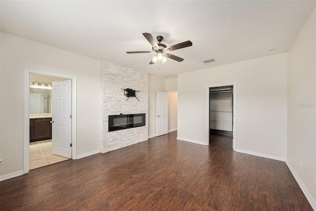 unfurnished living room with ceiling fan, a fireplace, wood finished floors, and baseboards