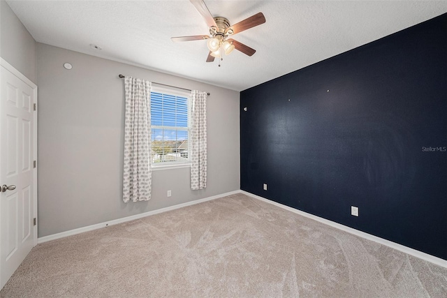 unfurnished room with a ceiling fan, carpet, a textured ceiling, and baseboards