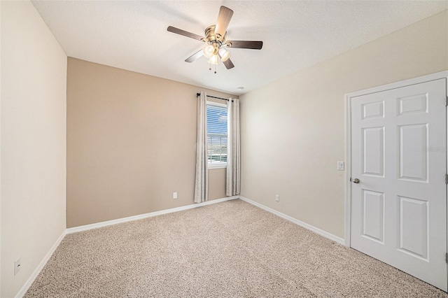 empty room featuring baseboards, ceiling fan, a textured ceiling, and light colored carpet