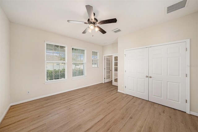 unfurnished bedroom with light wood-type flooring, baseboards, visible vents, and a closet