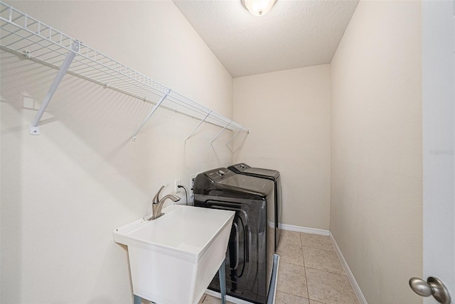 laundry room with laundry area, light tile patterned floors, baseboards, independent washer and dryer, and a sink