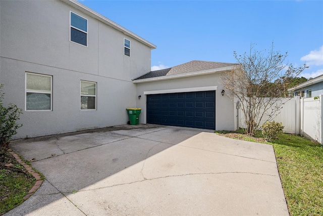 view of side of property with a garage, fence, concrete driveway, and stucco siding